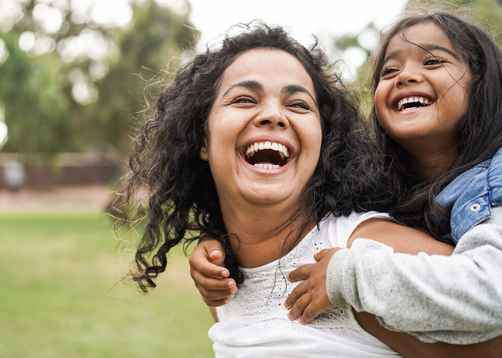 Happy mother and daughter laughing outside